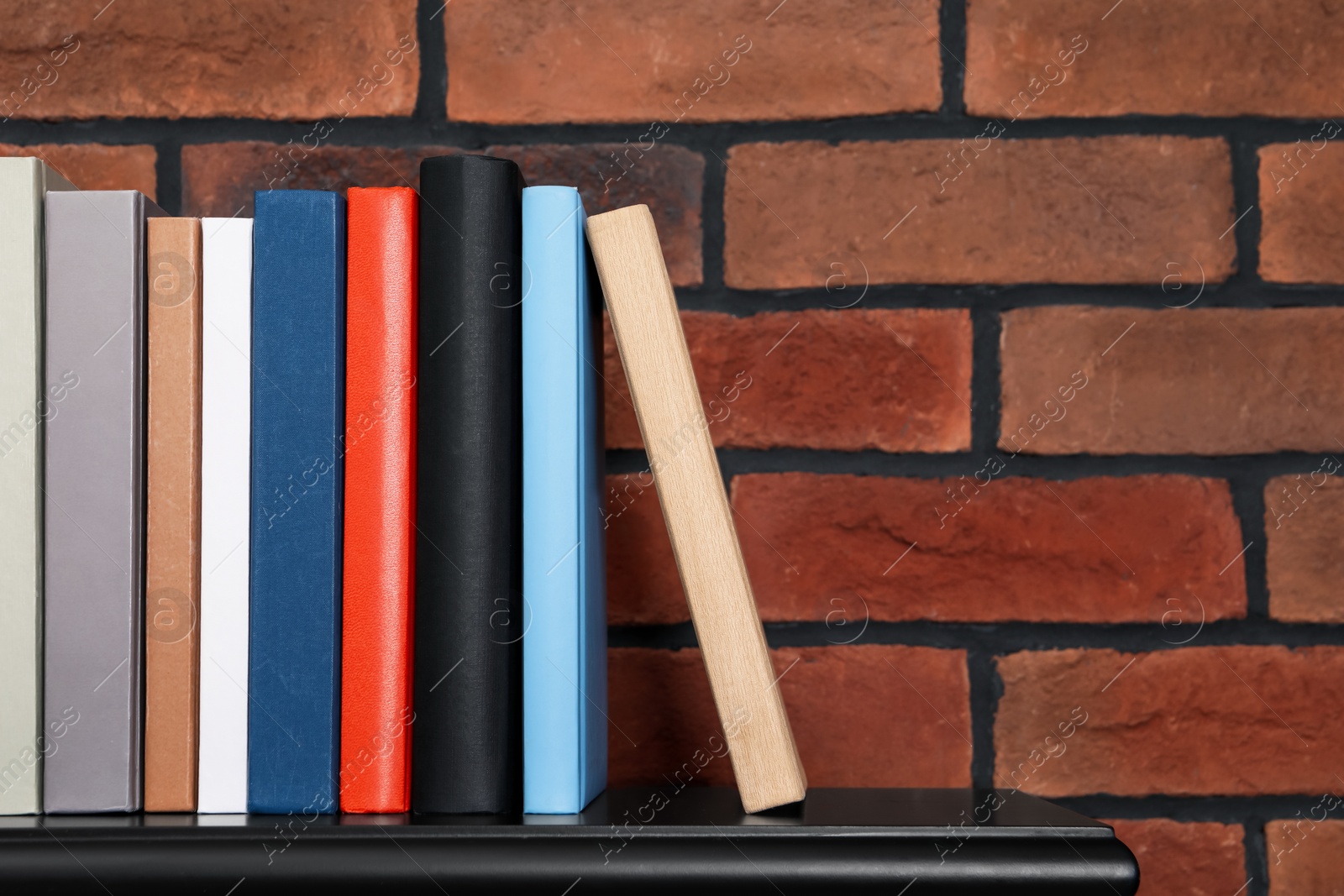 Photo of Many different hardcover books on black console table. Space for text