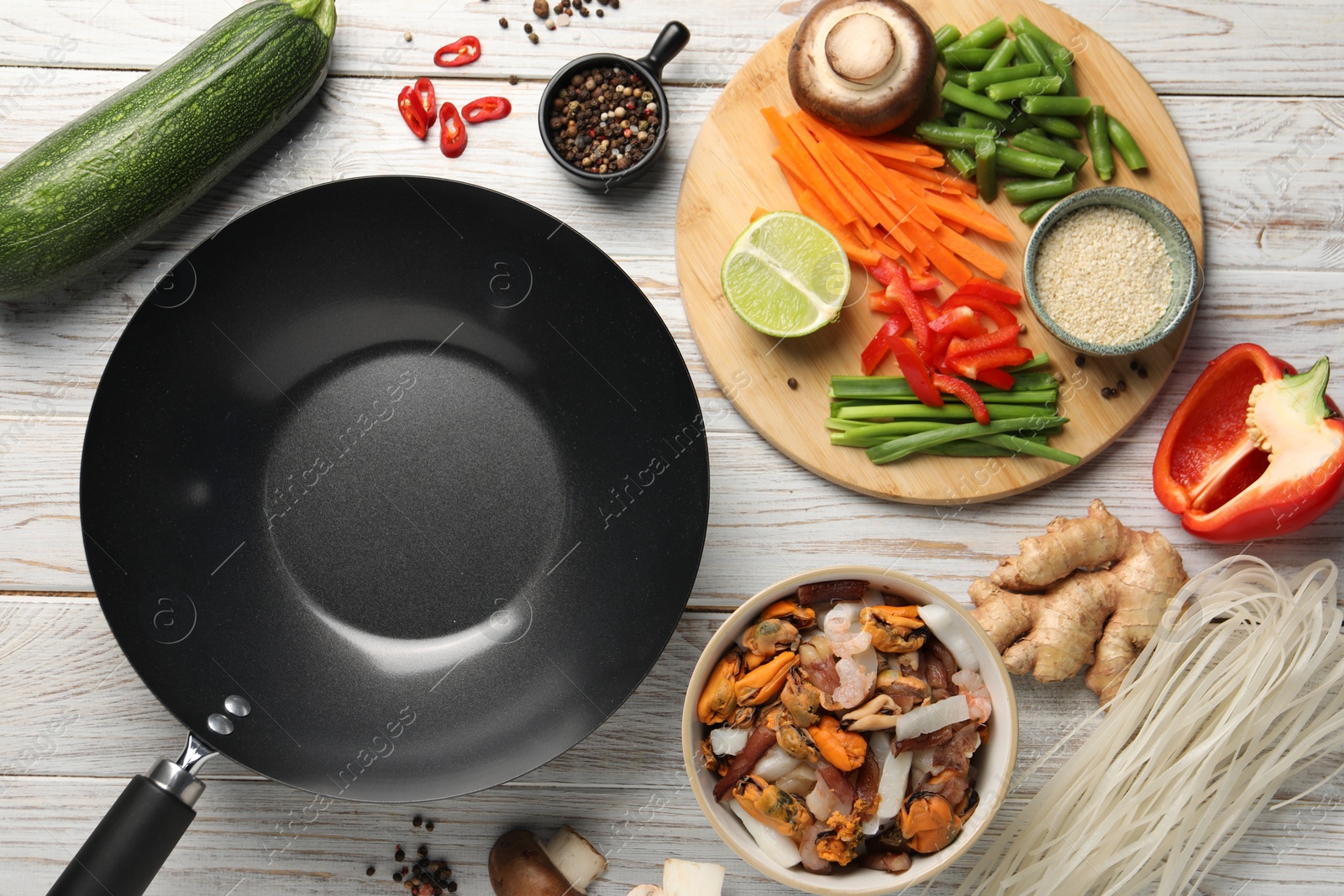 Photo of Flat lay composition with black wok and products on light wooden table