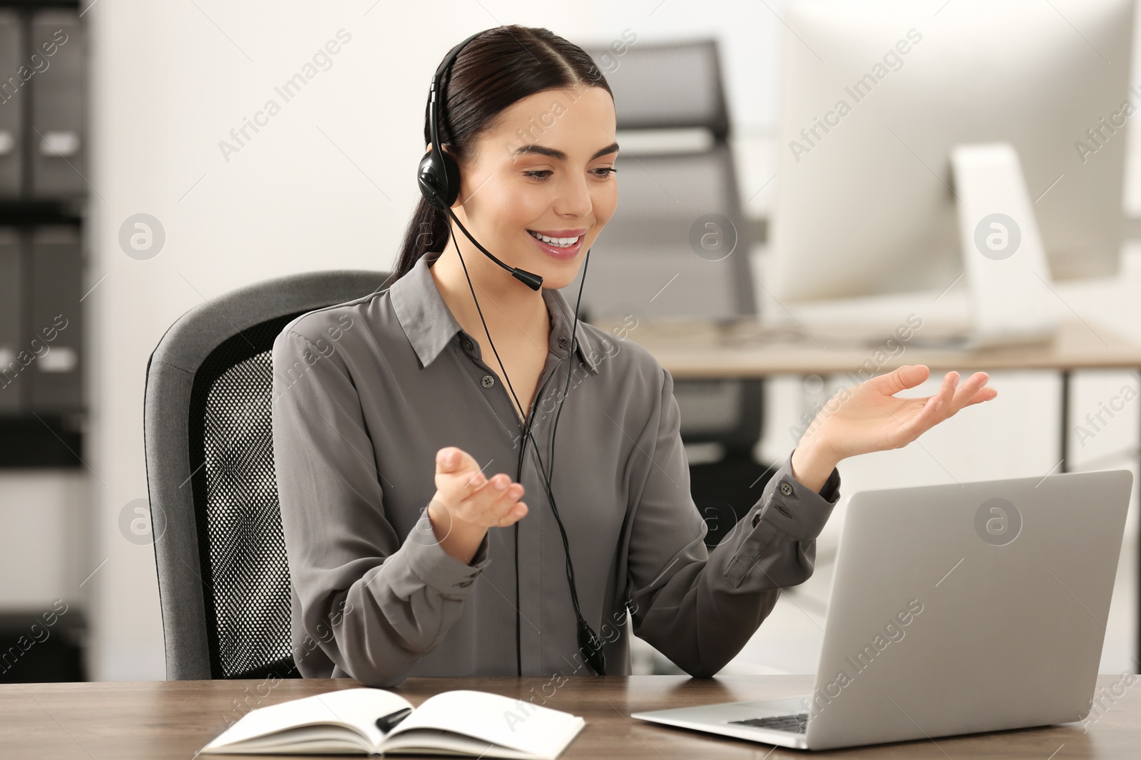 Photo of Hotline operator with headset working on laptop in office