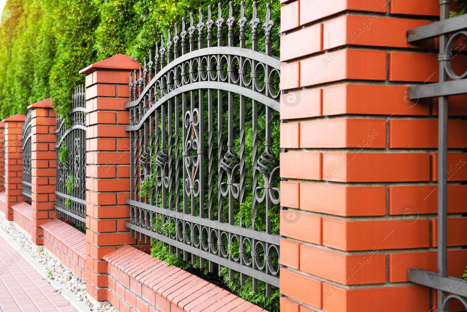 Photo of Beautiful brick fence with iron railing outdoors