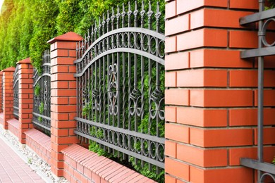 Photo of Beautiful brick fence with iron railing outdoors