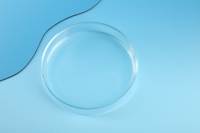 Empty petri dish on light blue background, above view