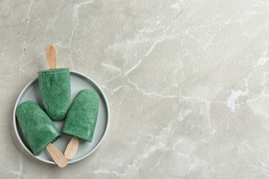Photo of Plate with delicious spirulina popsicles on grey background, top view. Space for text