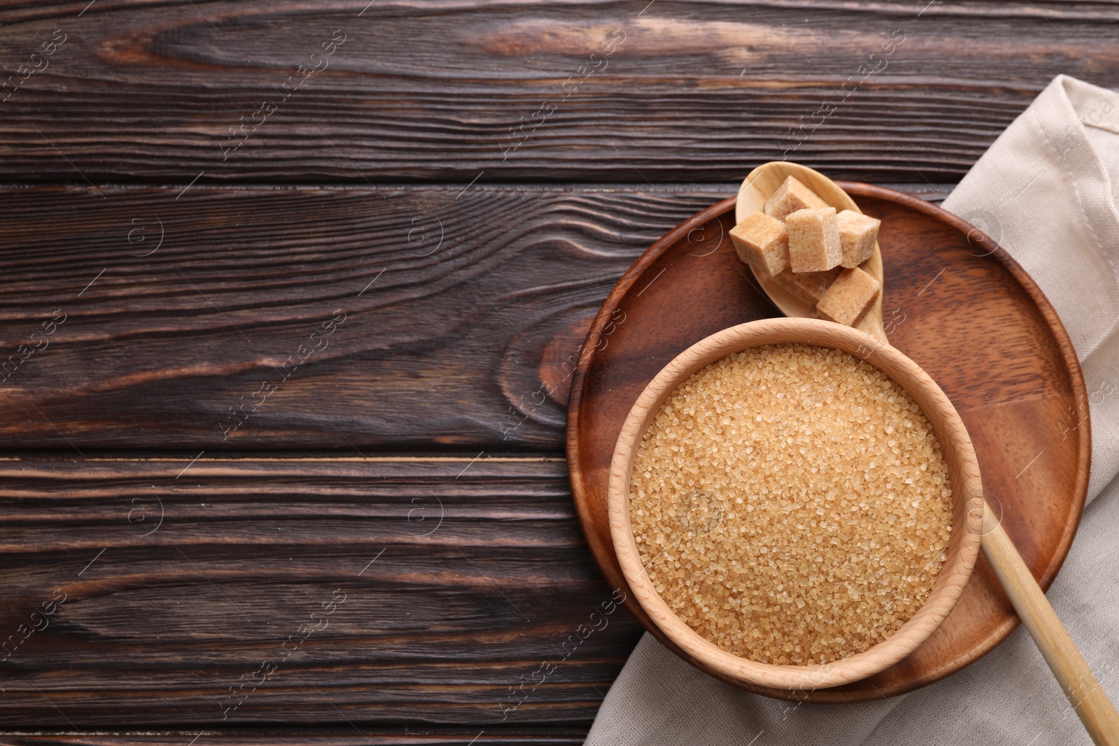 Photo of Bowl and spoon with brown sugar on wooden table, top view. Space for text