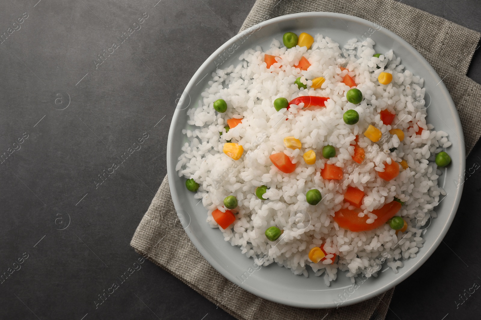 Photo of Delicious rice with vegetables on grey table, top view. Space for text
