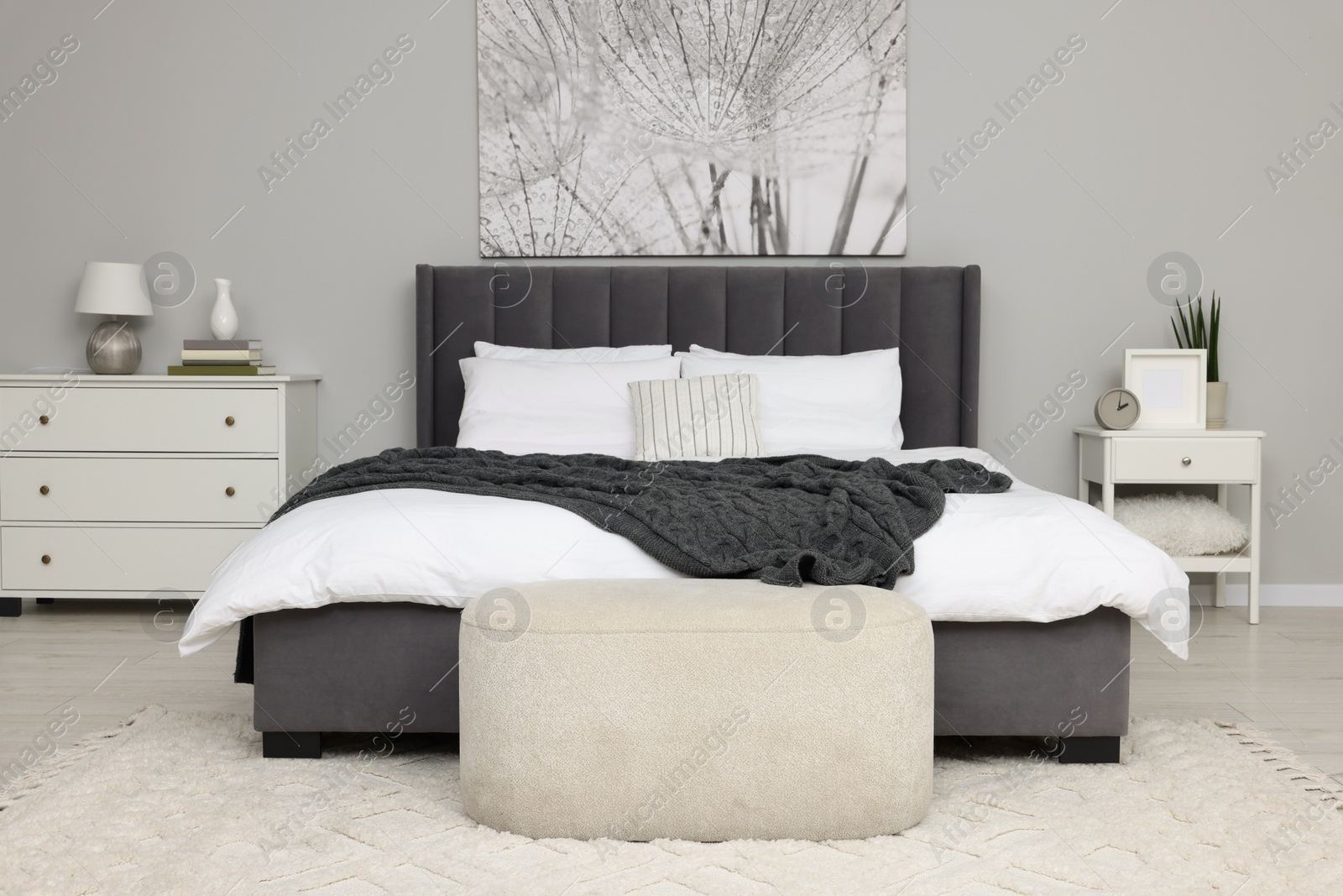 Photo of Stylish bedroom interior with large comfortable bed and ottoman