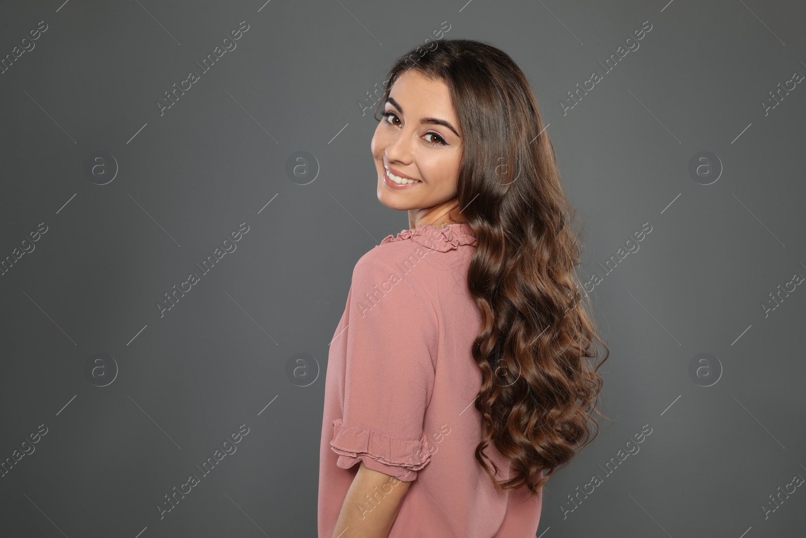 Photo of Beautiful woman with shiny wavy hair on grey background