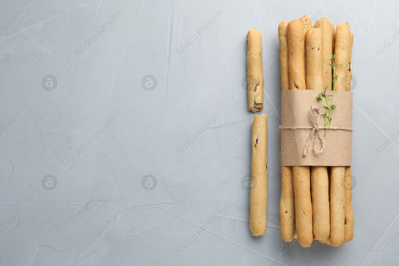 Photo of Delicious grissini sticks on light grey table, flat lay. Space for text