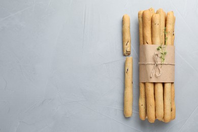 Delicious grissini sticks on light grey table, flat lay. Space for text