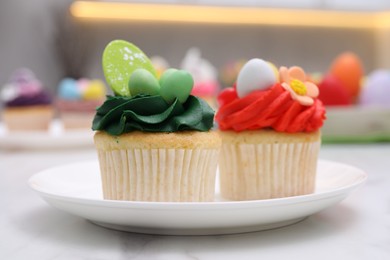 Photo of Tasty decorated Easter cupcakes on white marble table, closeup