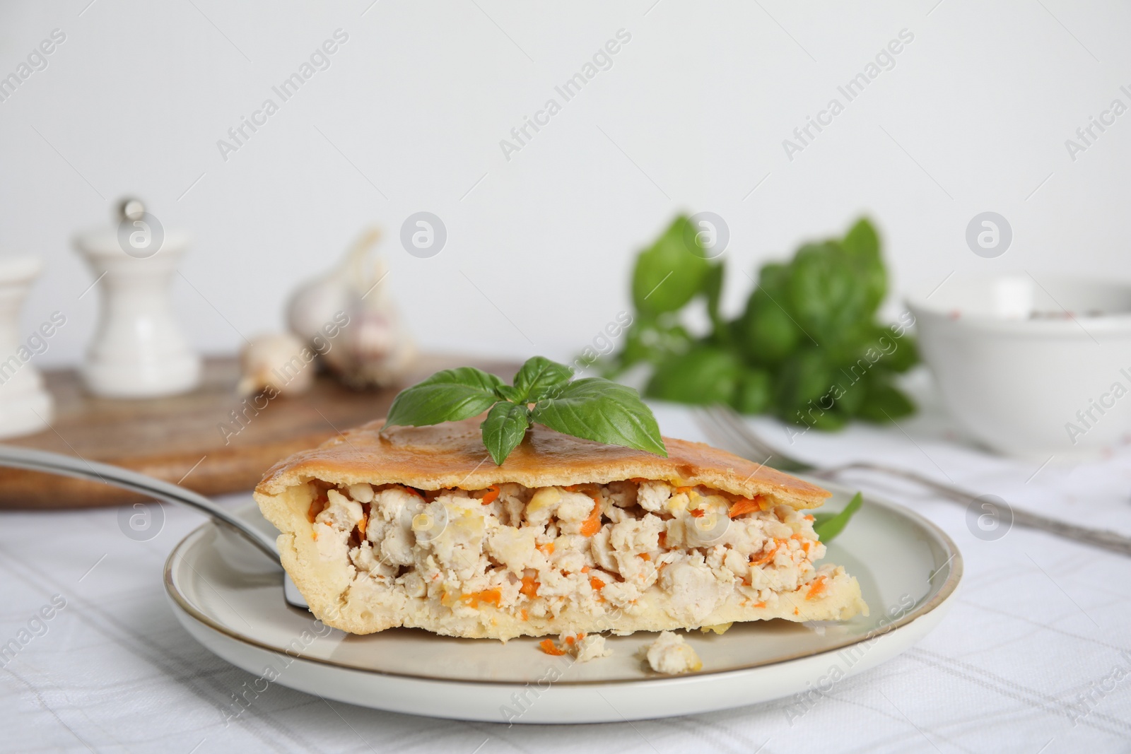 Photo of Slice of delicious meat pie with basil on table, space for text