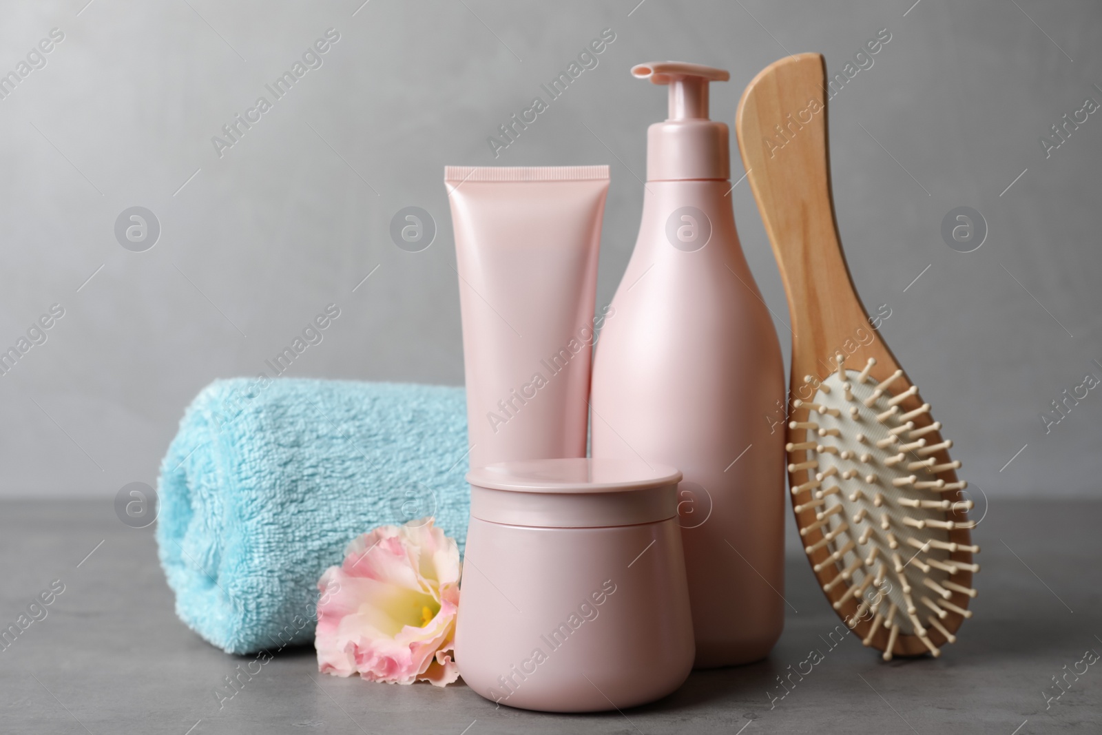 Photo of Different hair products, towel and brush on grey table