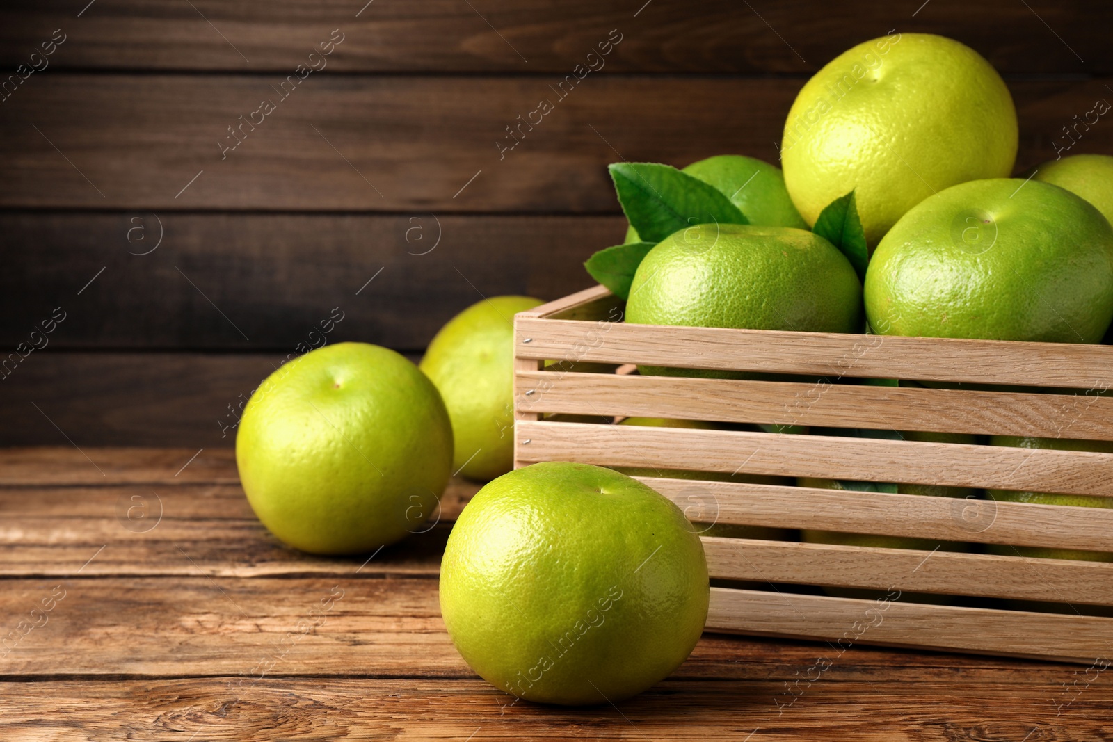 Photo of Fresh ripe sweetie fruits in crate on wooden table