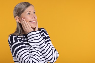 Photo of Portrait of happy surprised senior woman on yellow background, space for text