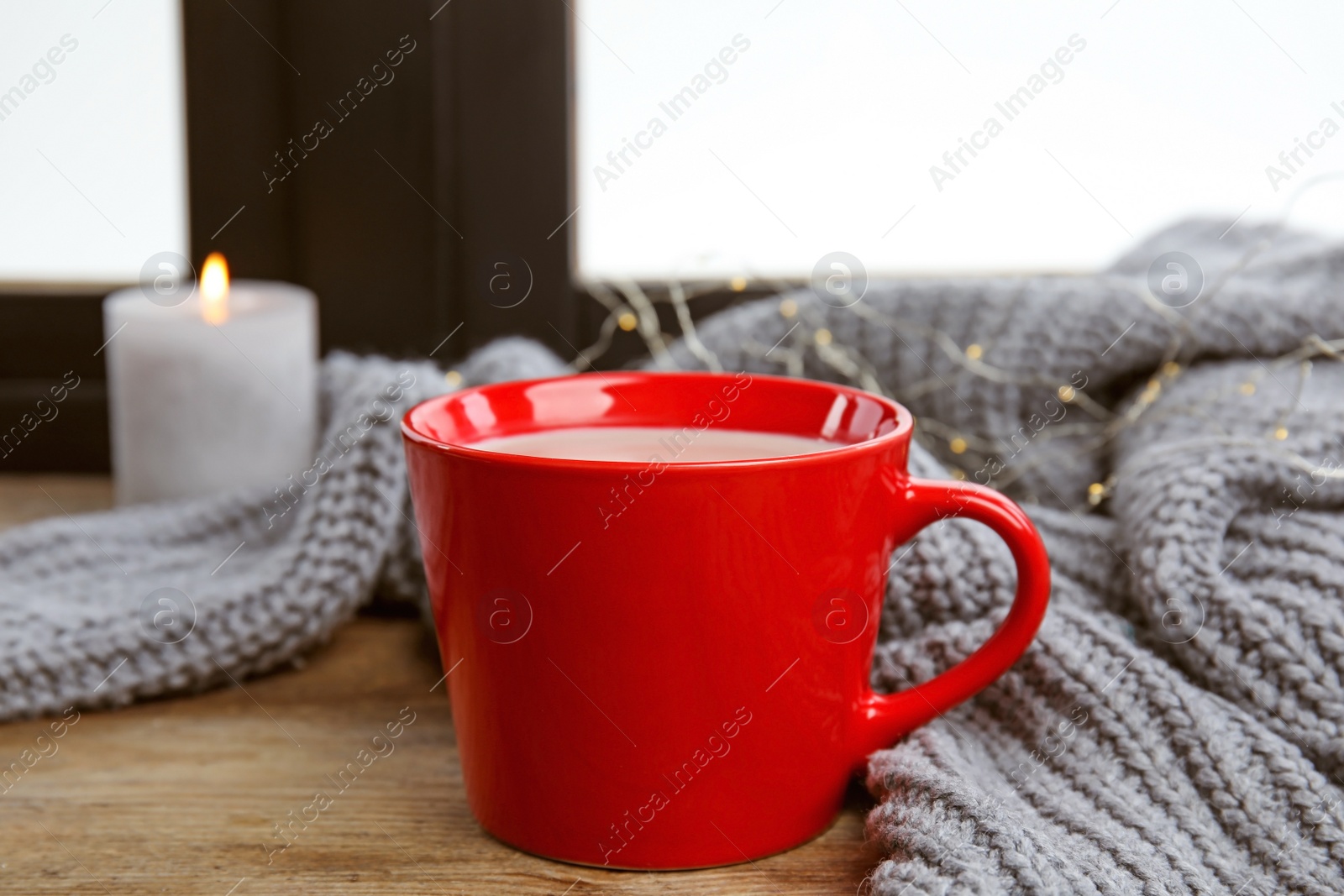 Photo of Cup of hot cocoa and sweater on window sill. Winter drink