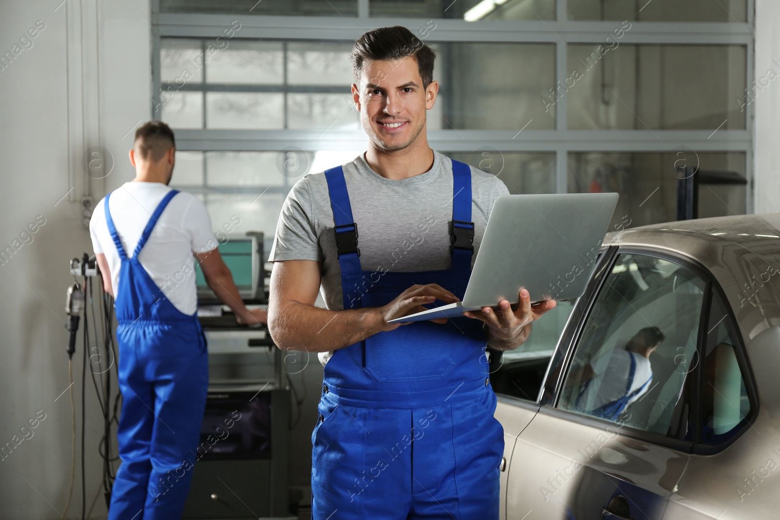 Photo of Mechanic with laptop doing car diagnostic at automobile repair shop