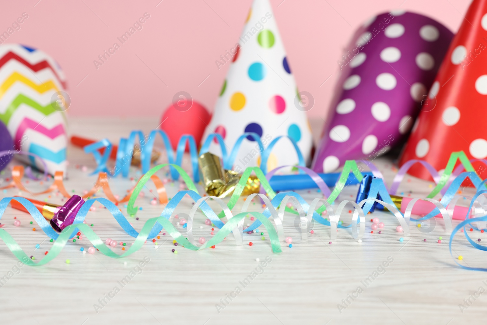 Photo of Colorful serpentine streamers and other party accessories on white wooden table