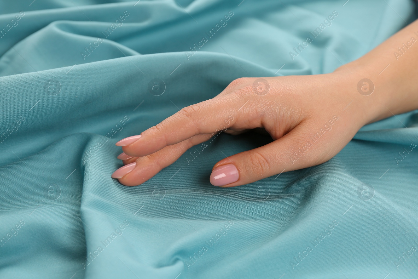 Photo of Woman touching soft turquoise fabric, closeup view