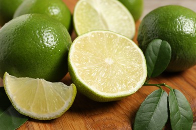 Photo of Fresh ripe limes on wooden board, closeup