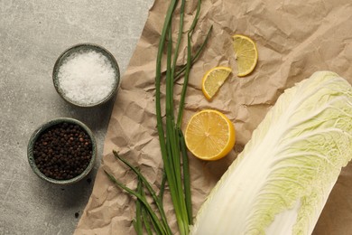 Photo of Fresh Chinese cabbage, lemon, green onion and spices on light grey table, flat lay