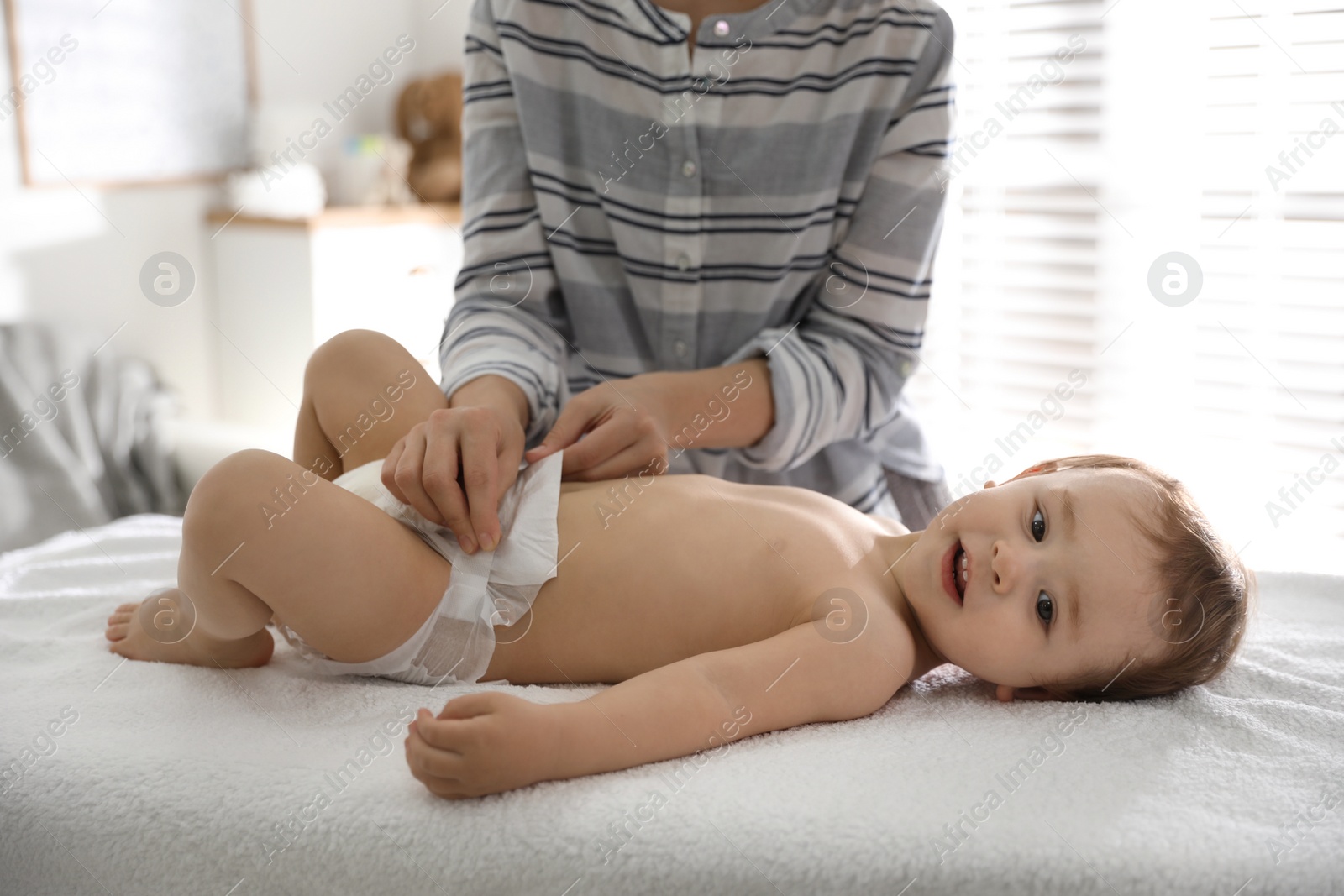 Photo of Mother changing baby's diaper on table at home