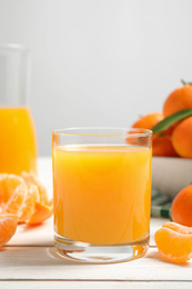 Photo of Glass of fresh tangerine juice and fruits on white wooden table