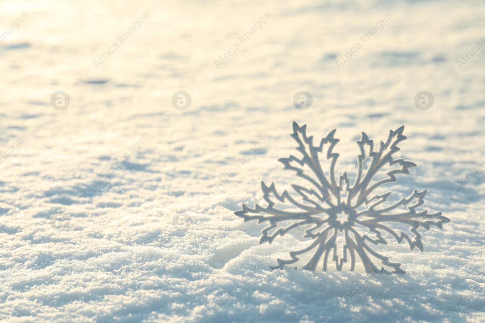 Photo of Beautiful decorative snowflake in white snow, outdoors. Space for text