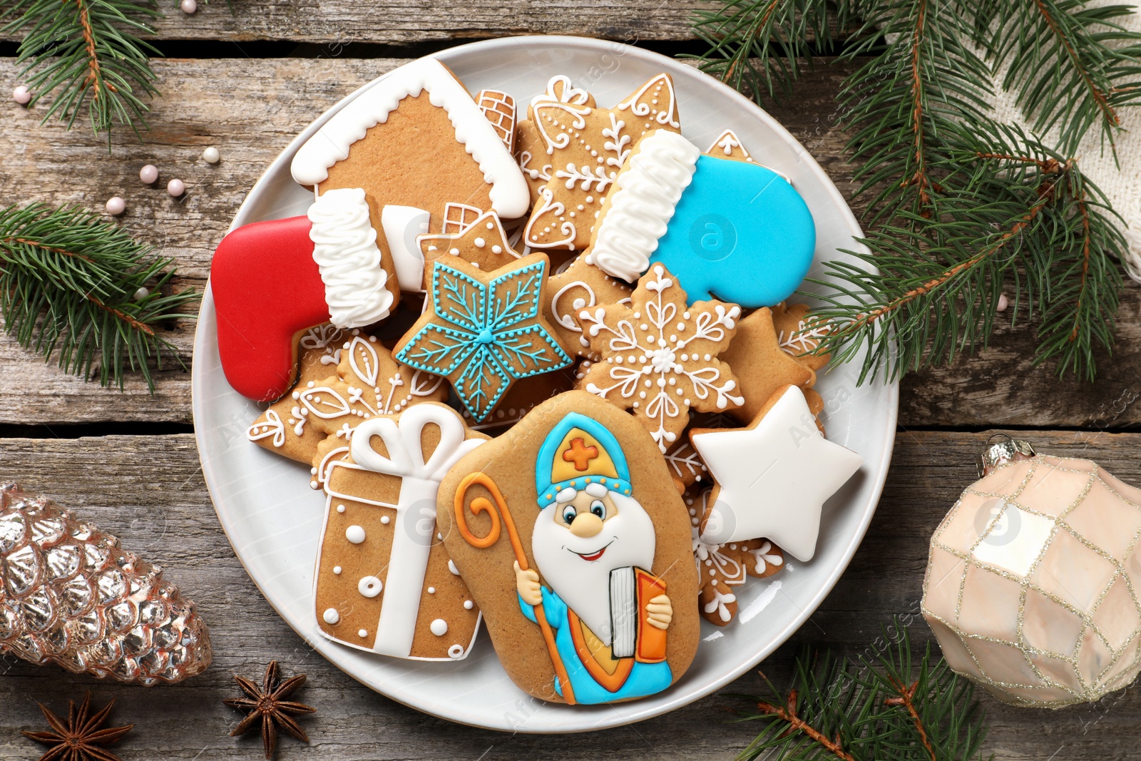 Photo of Tasty gingerbread cookies and festive decor on wooden table, flat lay. St. Nicholas Day celebration