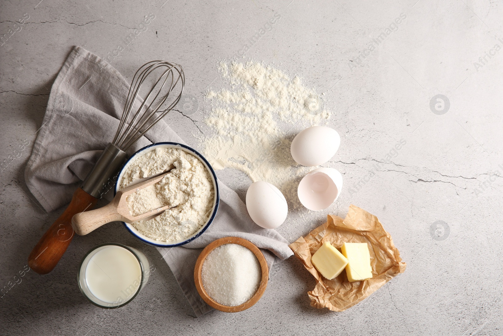Photo of Different ingredients for dough and whisk on light textured table, flat lay
