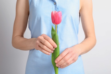 Photo of Girl holding beautiful spring tulip on light background, closeup. International Women's Day