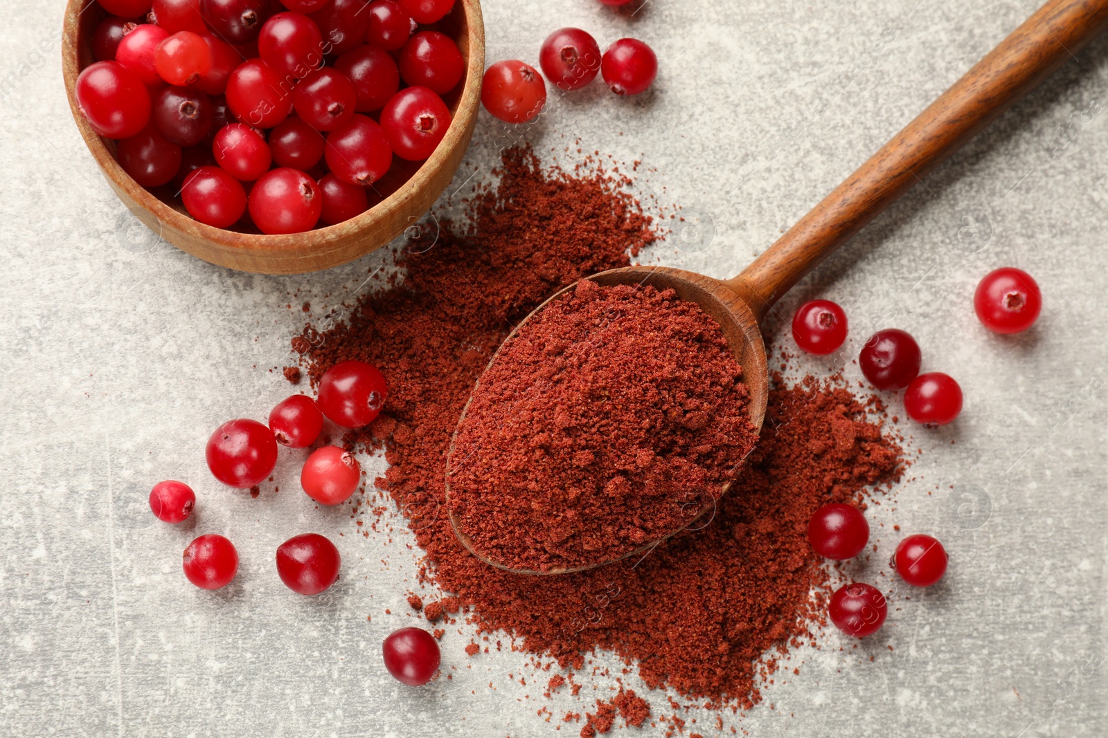 Photo of Pile of cranberry powder and fresh berries on light grey table, top view