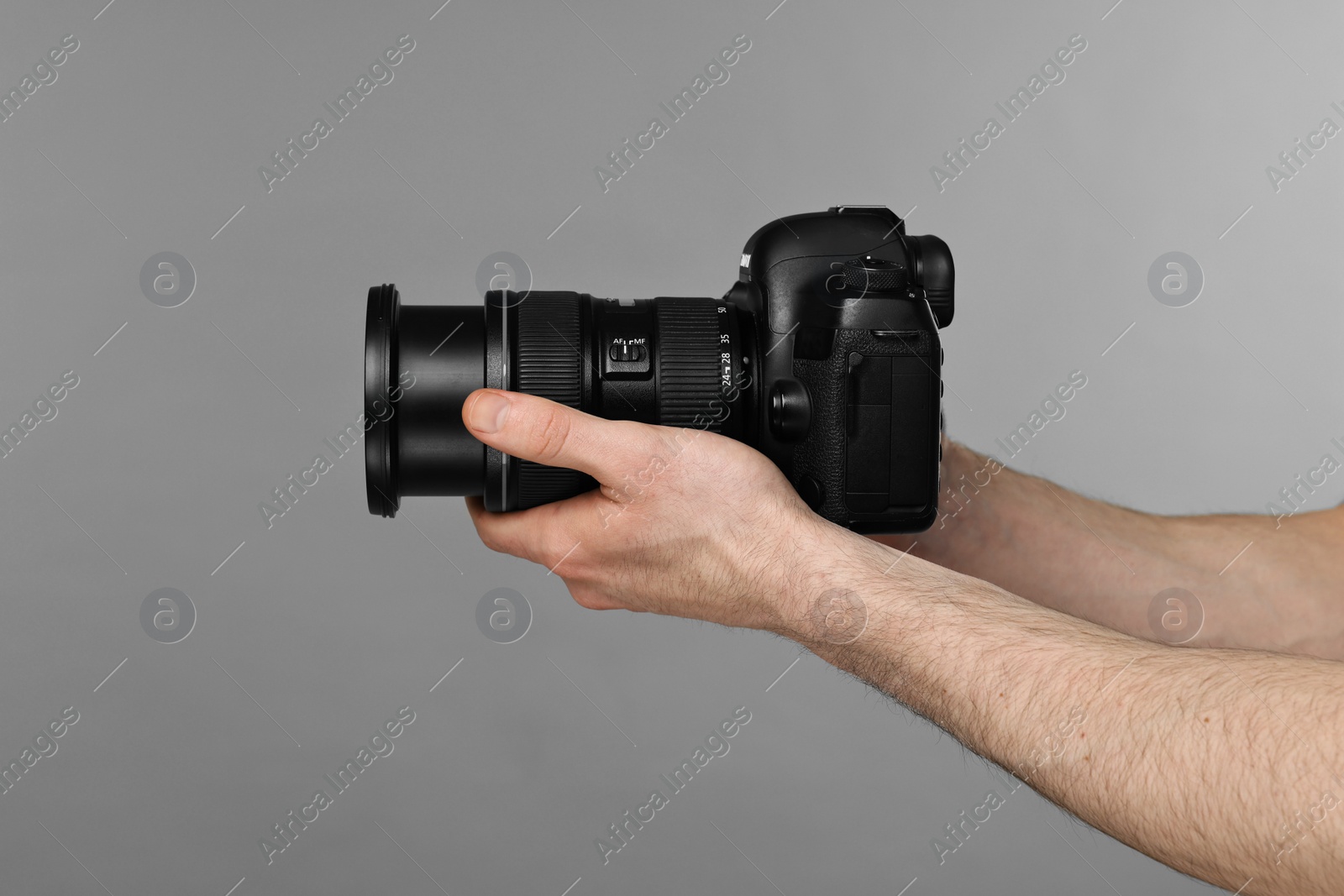 Photo of Photographer holding camera on grey background, closeup