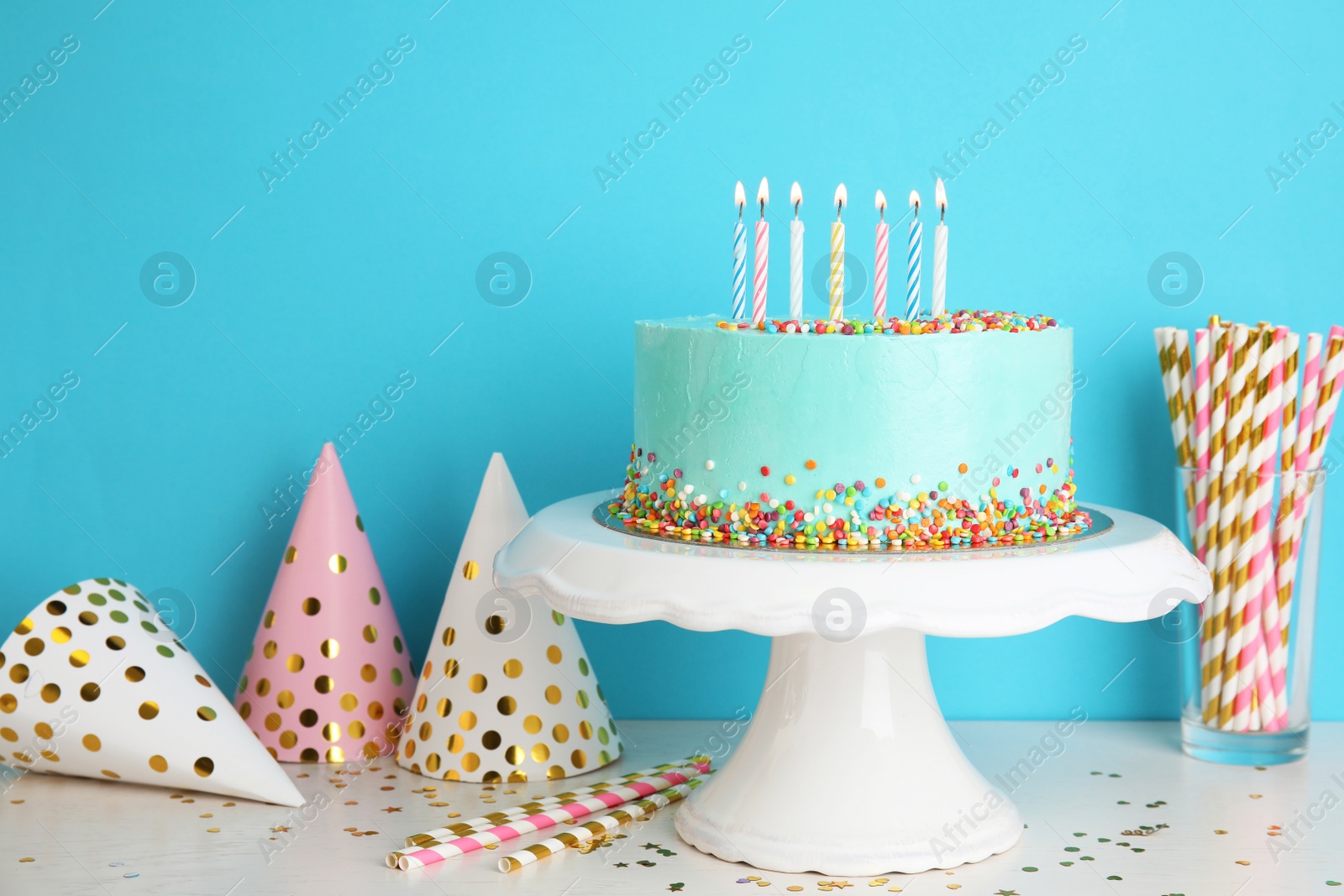 Photo of Fresh delicious cake and birthday caps on table against color background. Space for text