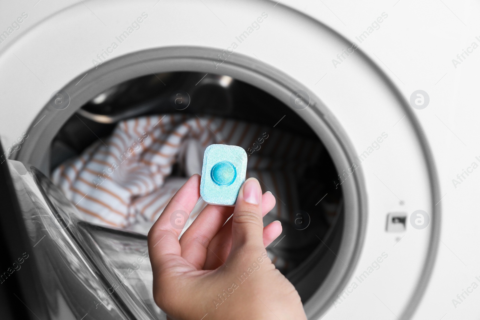 Photo of Woman putting water softener tablet into washing machine, closeup