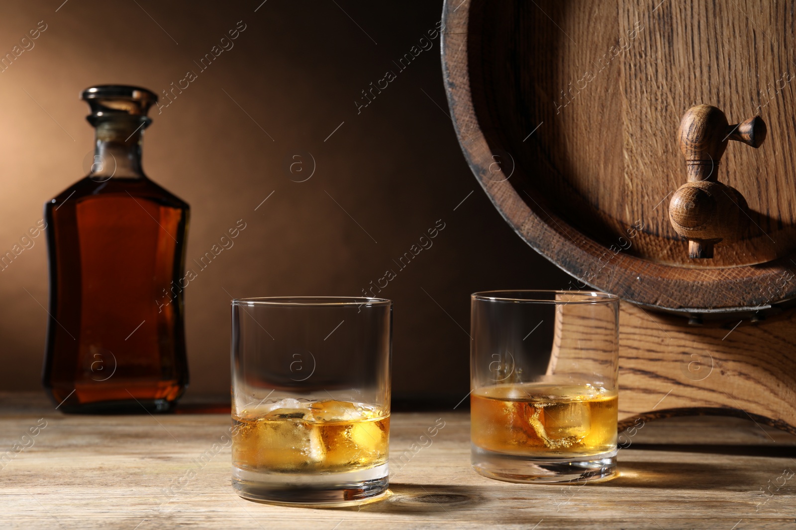 Photo of Barrel with tap and tasty whiskey on wooden table