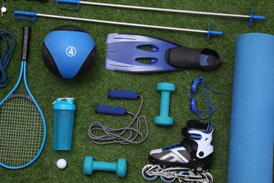 Different sport equipment on green grass, flat lay