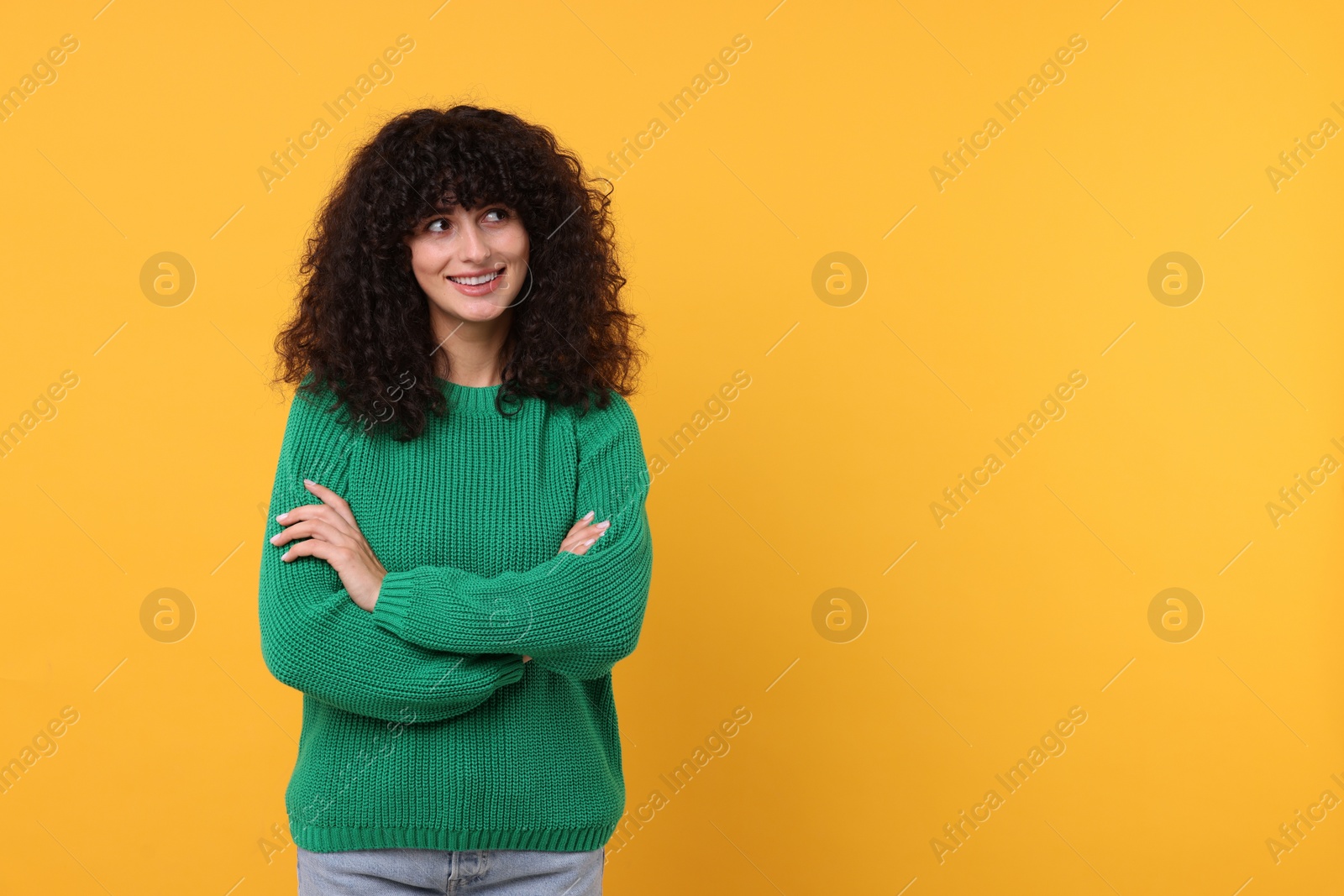 Photo of Happy young woman in stylish green sweater on yellow background, space for text