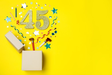 Photo of Flat lay composition with decor and numbers on yellow background, space for text. 45th birthday party
