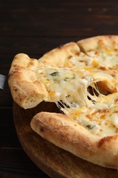 Photo of Taking piece of delicious cheese pizza at wooden table, closeup