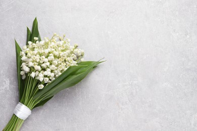 Beautiful lily of the valley bouquet on grey table, top view. Space for text