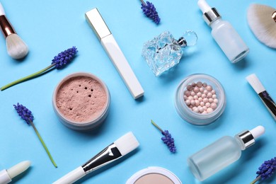 Flat lay composition with different makeup products and beautiful spring flowers on light blue background