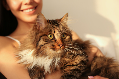Photo of Woman with her cute cat on bed, closeup. Fluffy pet