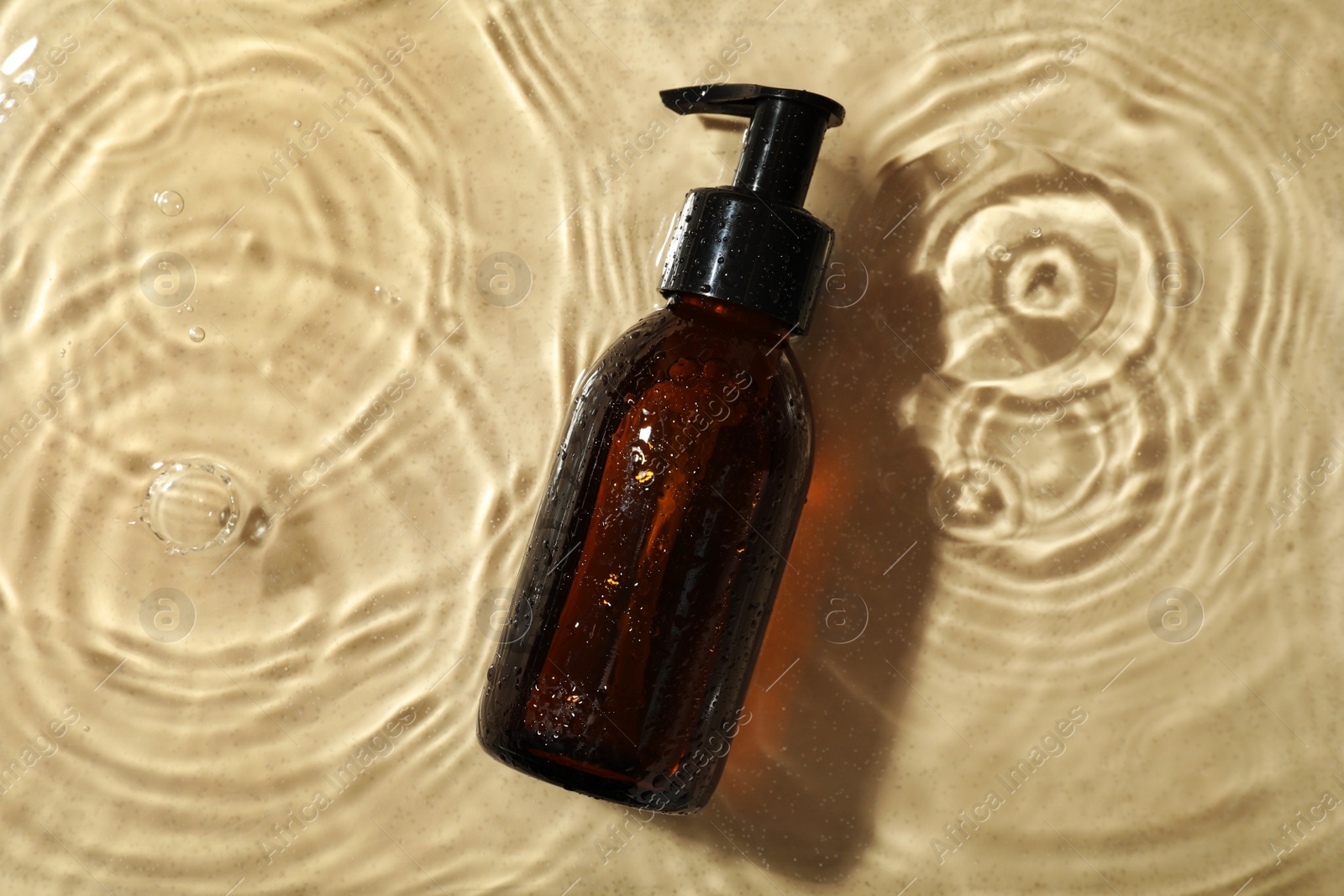 Photo of Bottle of hydrophilic oil in water on beige background, top view