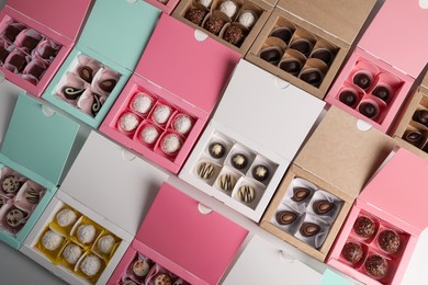 Photo of Boxes with delicious candies on white table, flat lay. Production line