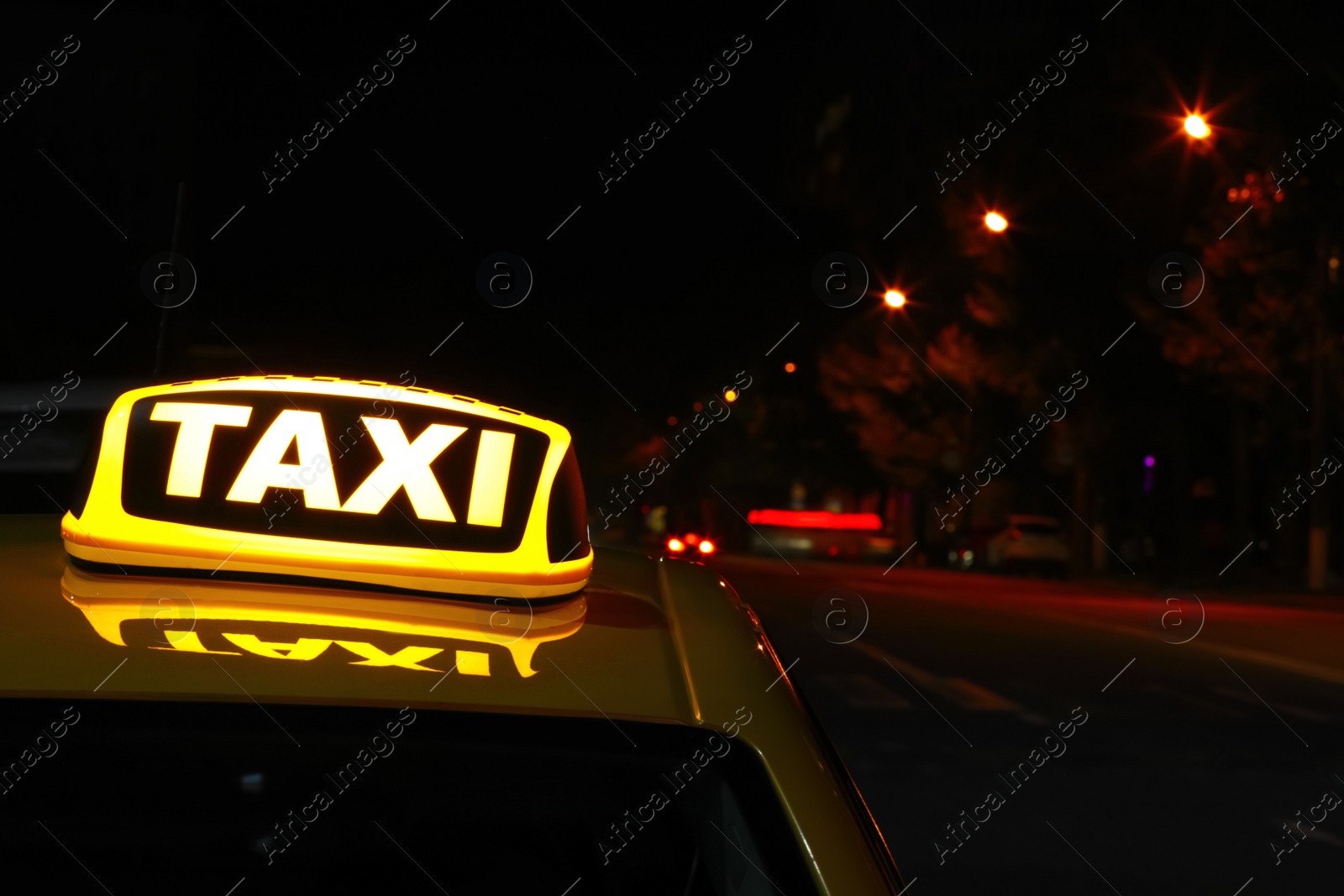 Photo of Taxi car with yellow sign on city street at night