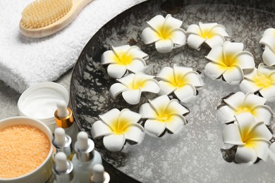 Bowl of water with flowers and different spa supplies on table