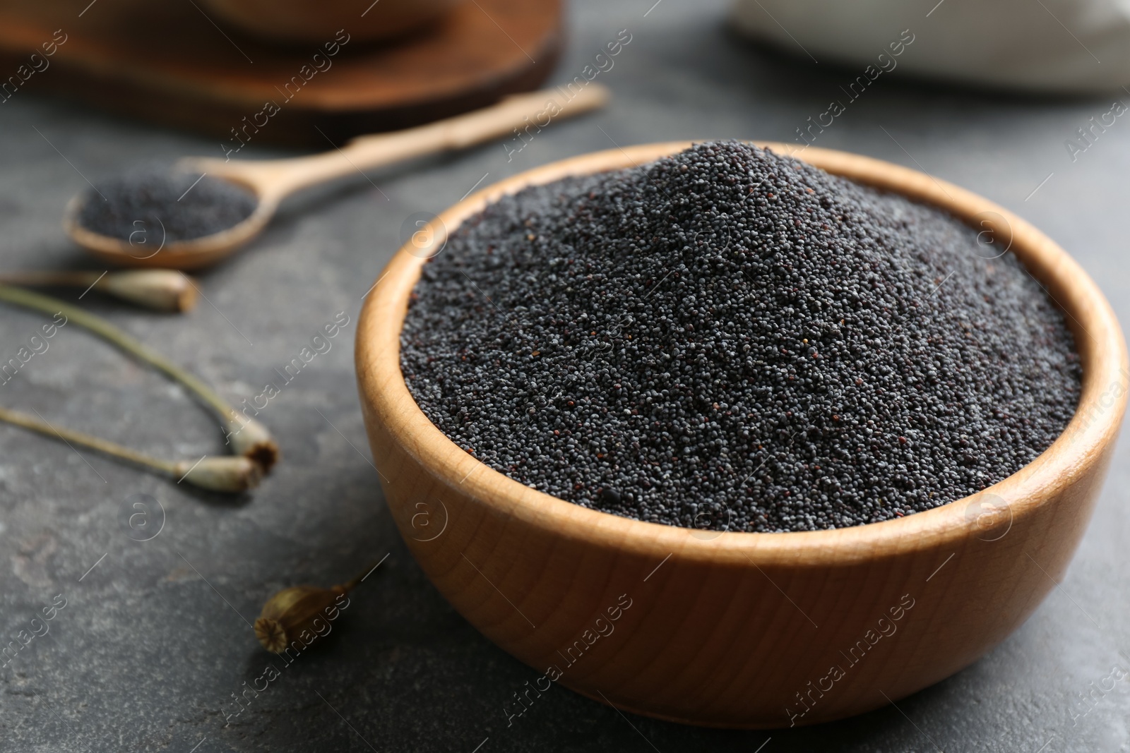 Photo of Poppy seeds in bowl on grey table