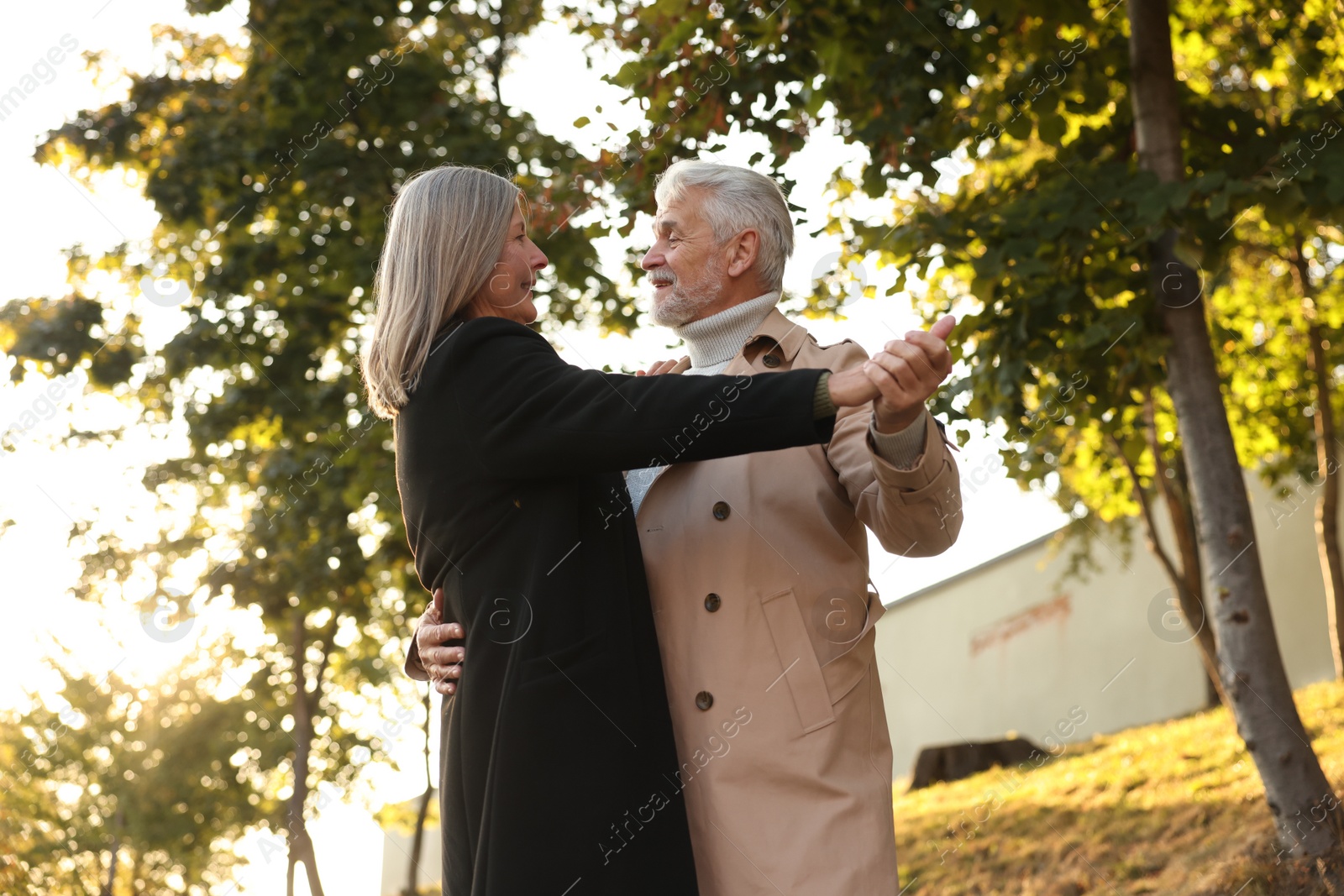 Photo of Affectionate senior couple dancing together outdoors, low angle view