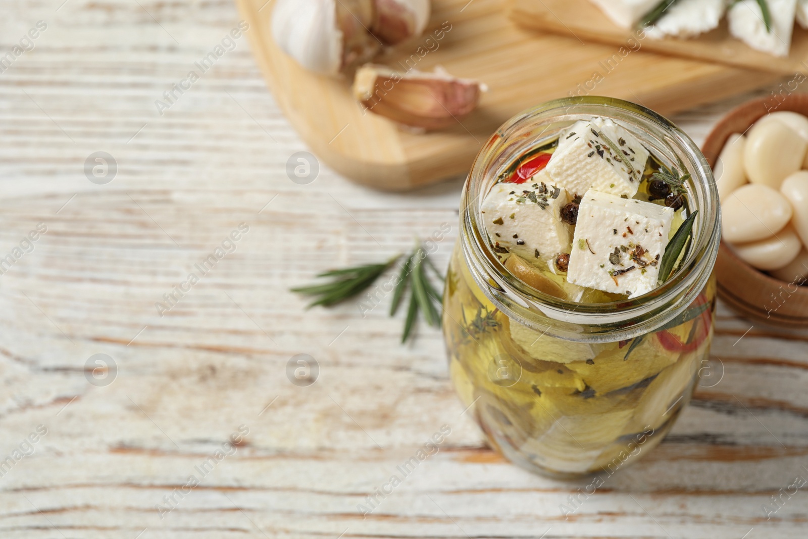 Photo of Composition with pickled feta cheese in jar on white wooden table, space for text