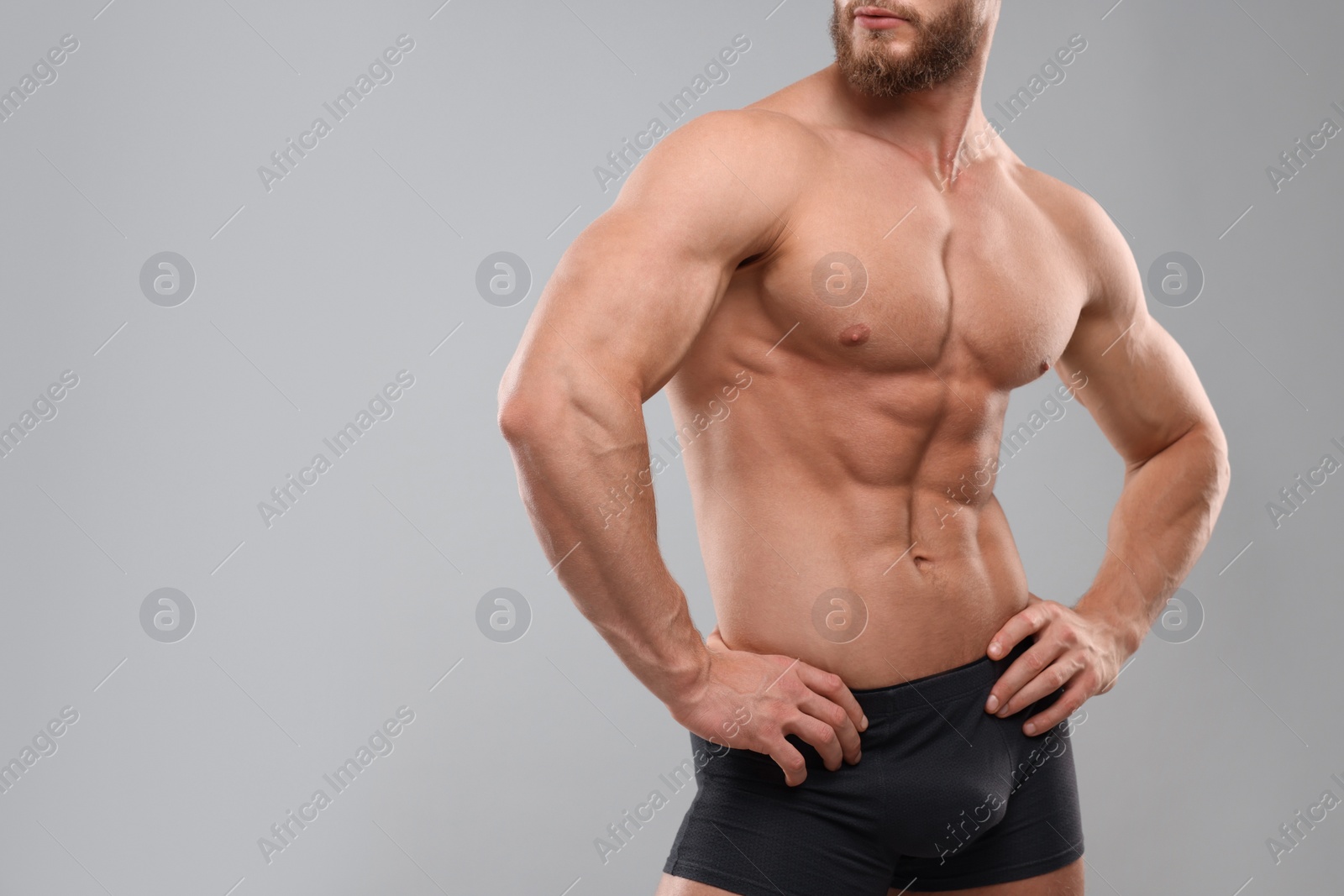 Photo of Muscular man showing abs on light grey background, closeup and space for text. Sexy body